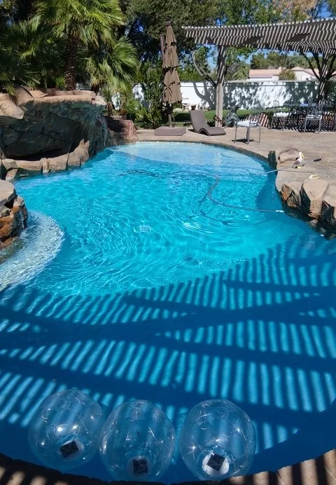 Pool water beside a rock feature with striped shade across the surface.
