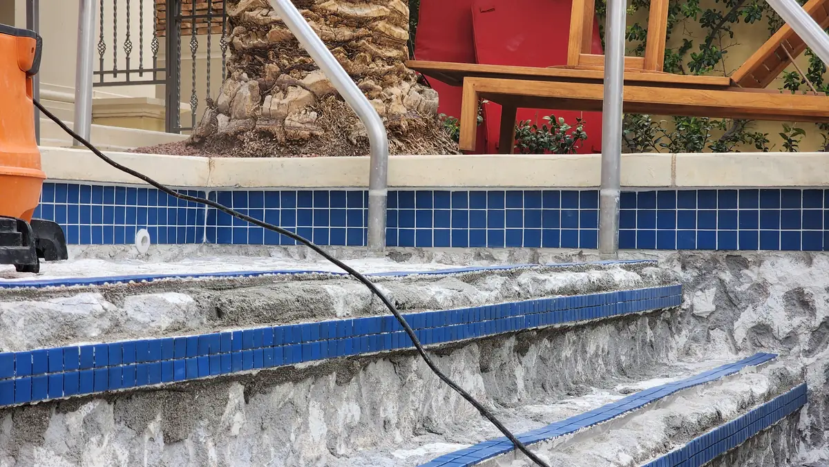 Tile along the waterline and steps of a drained pool.