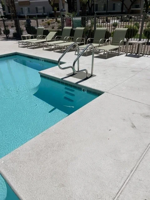 Metal entry handrails beside blue-tiled pool steps.