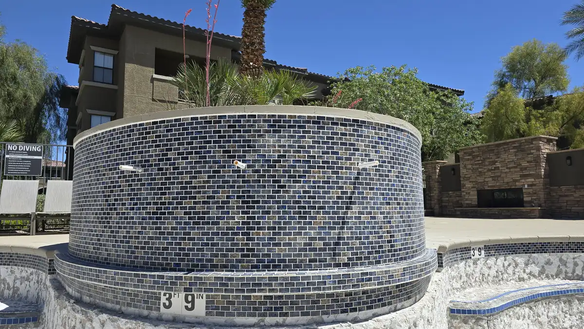 Glass mosaic tile on a raised spa wall above a drained pool.