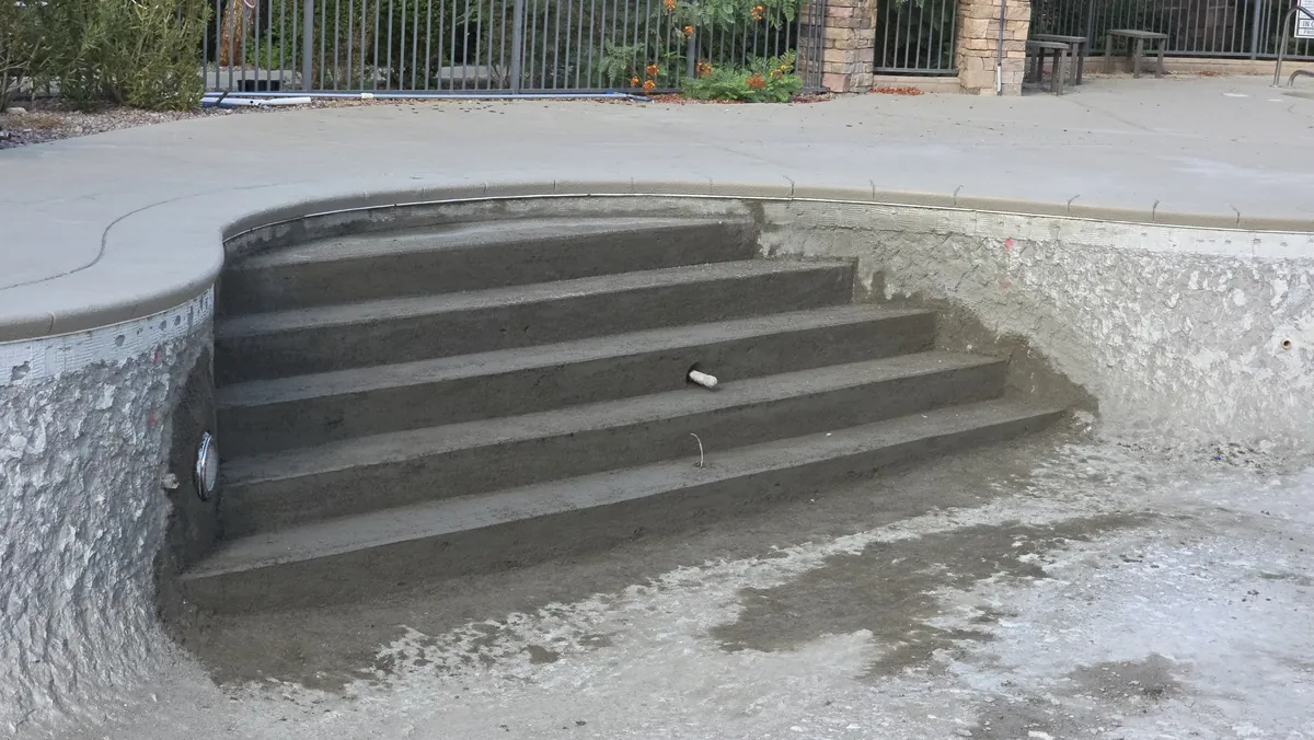 Newly formed shotcrete entry steps in an empty pool.