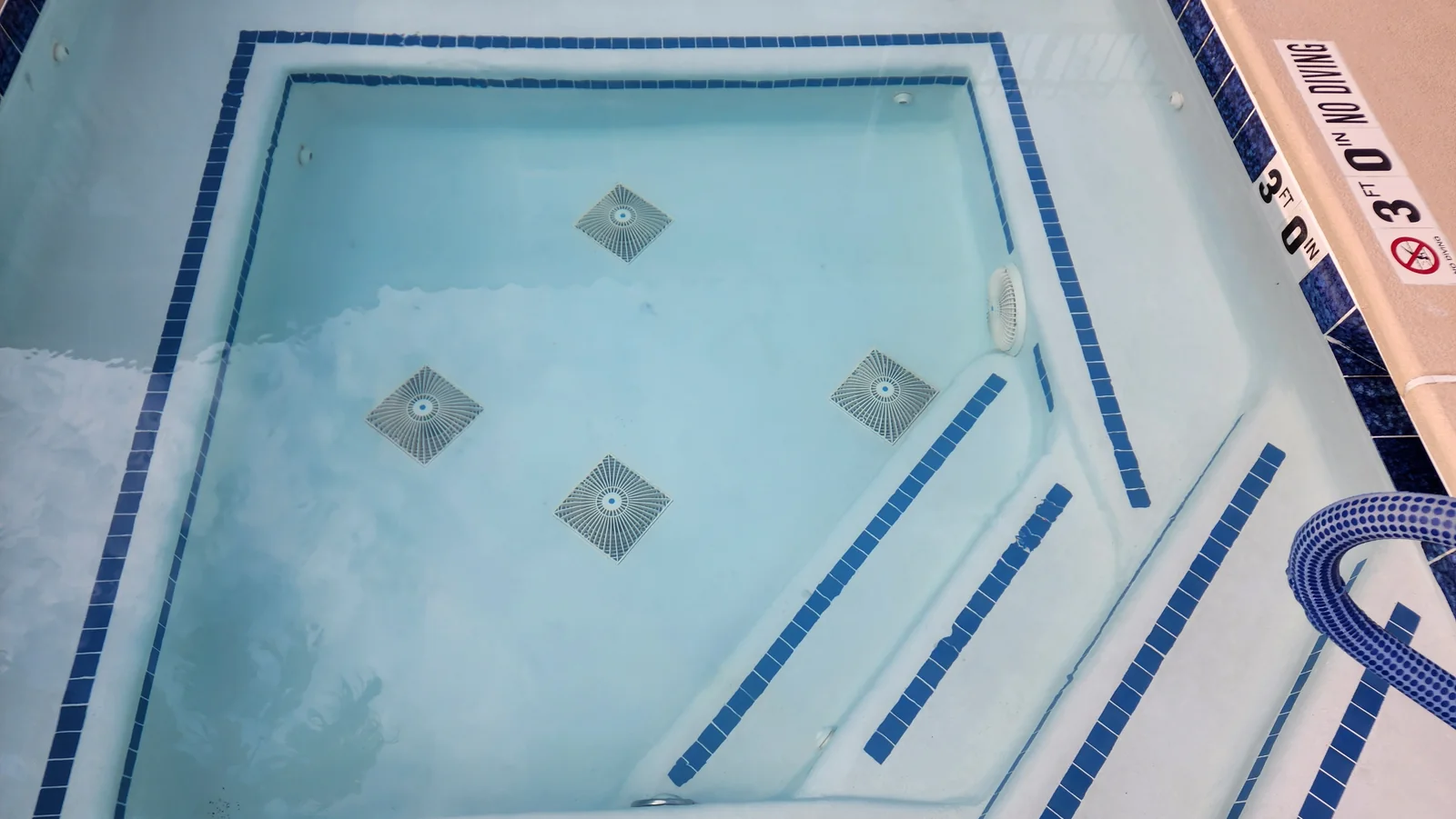 Three square drain covers in a newly plastered pool floor.