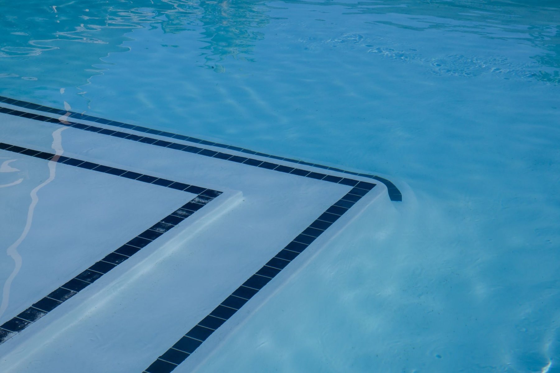 Clear blue pool water over a smooth finish and tiled steps