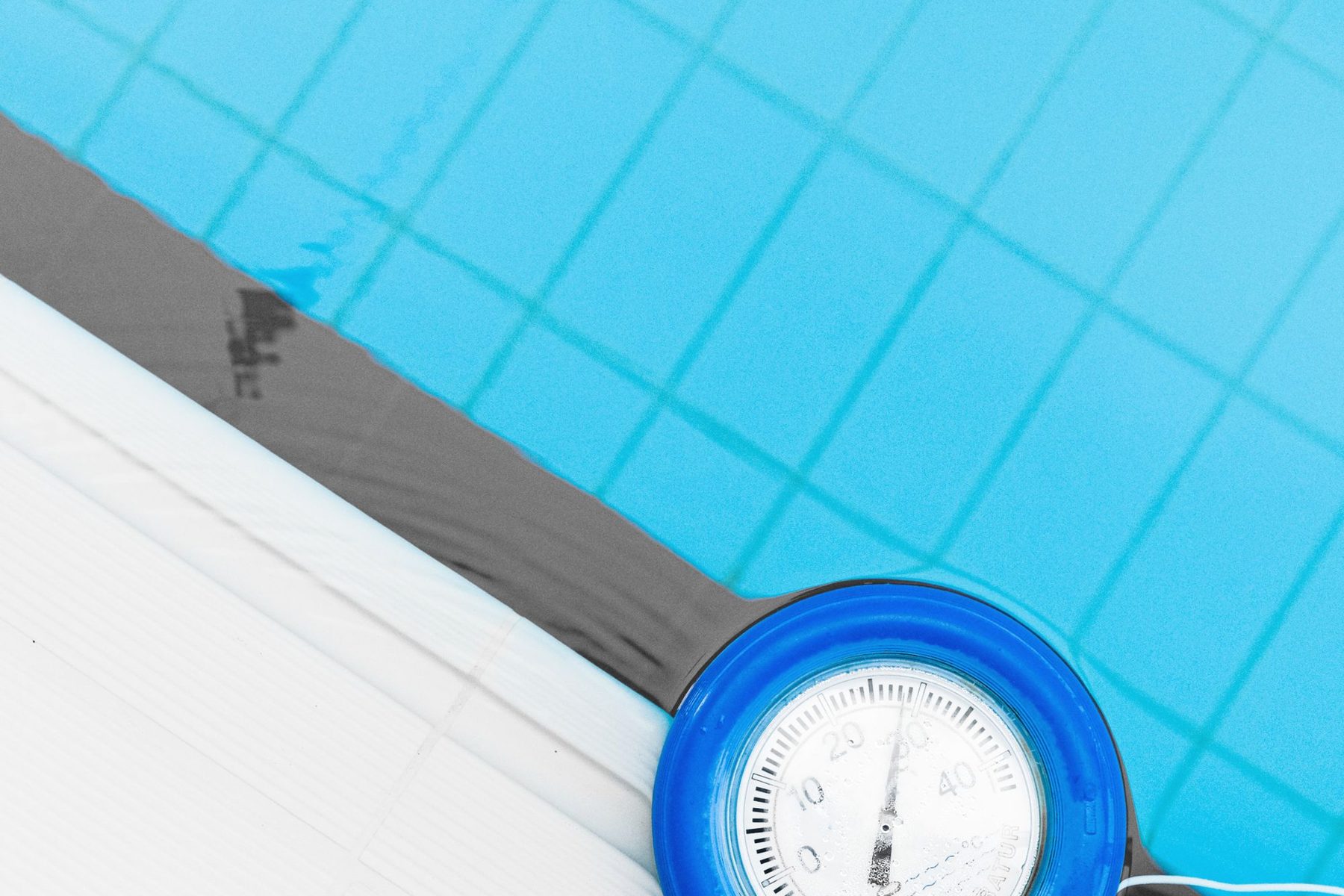 Blue commercial pool with a floating thermometer at the edge