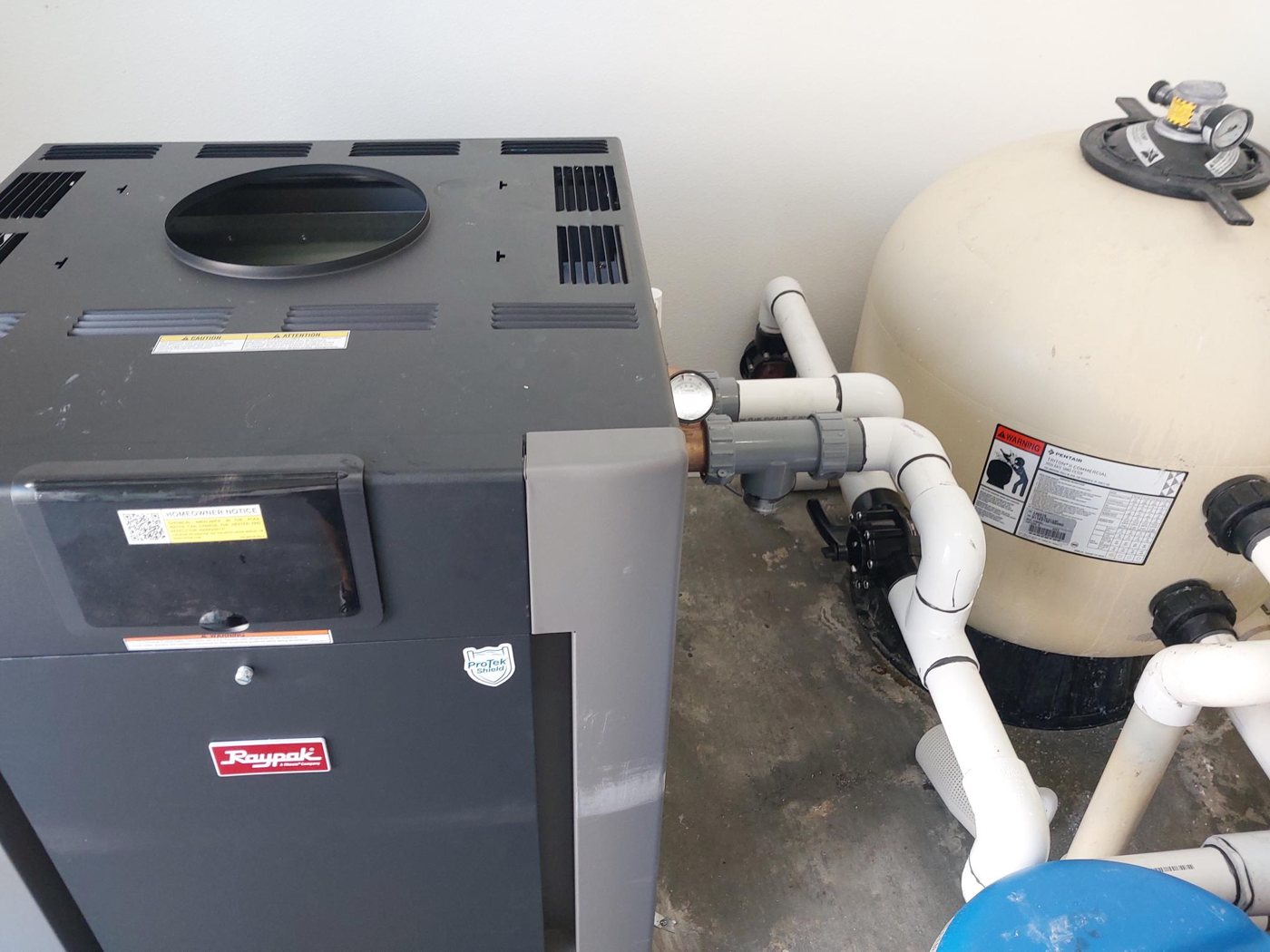 Commercial pool heater beside a sand filter
