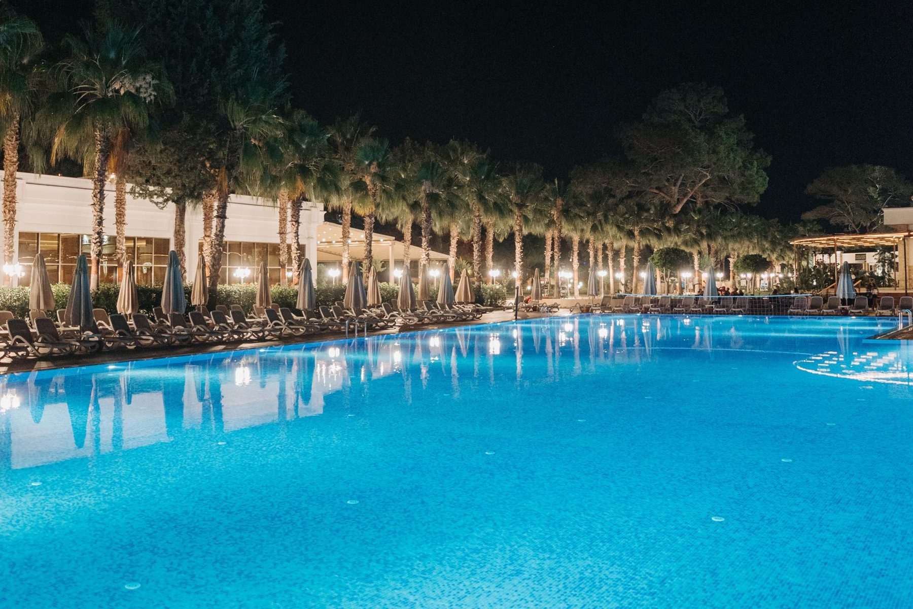 Large resort-style commercial pool lit at night