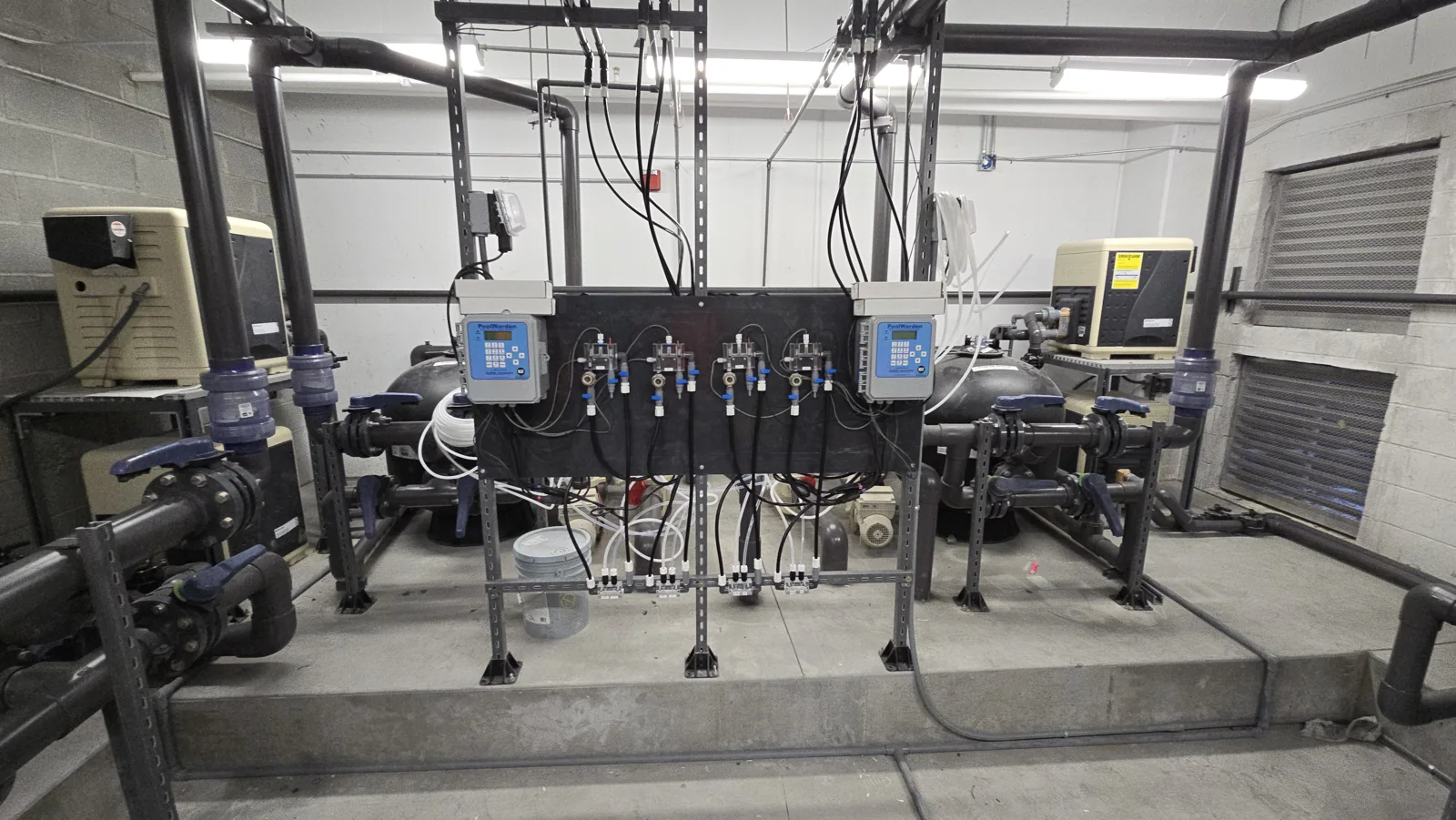 Commercial filtration equipment and connected pipes in a pump room.