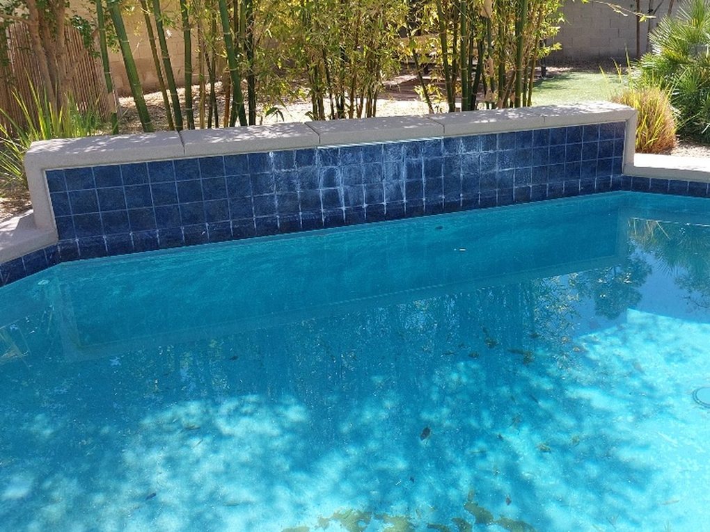 Raised pool wall tile streaked with white calcium buildup
