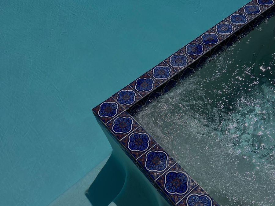 Patterned blue tile border beside pool water.