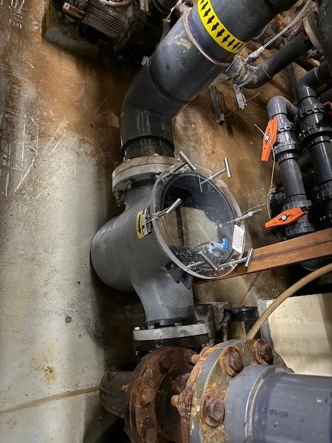 Commercial pump strainer housing and connected large-diameter pipes.