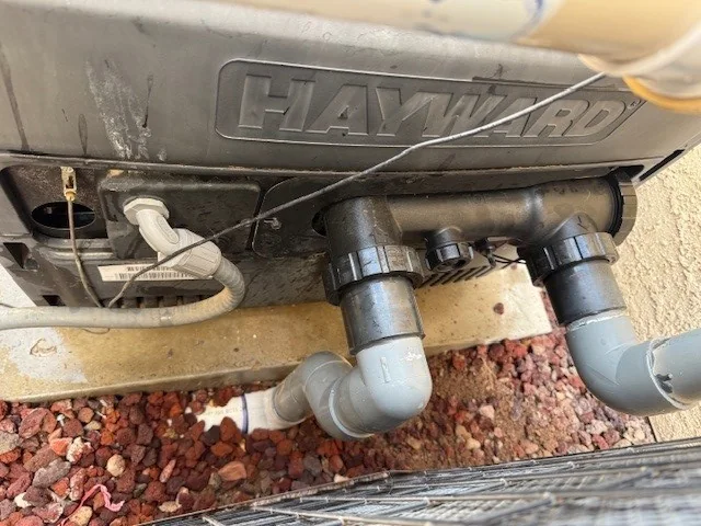 Pool heater inlet and outlet plumbing beneath the cabinet.