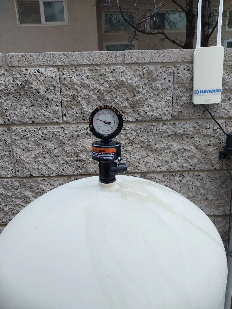Pressure gauge and air-release valve on a cartridge-filter tank.