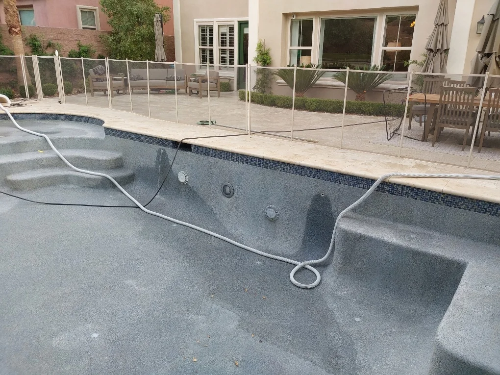 Tile waterline and coping beside a drained pool and entry steps.