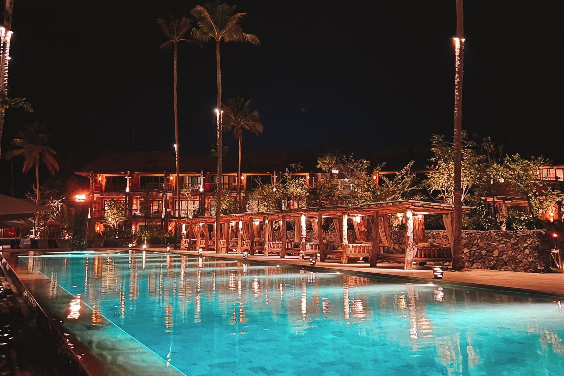 Resort pool glowing with underwater lights at night