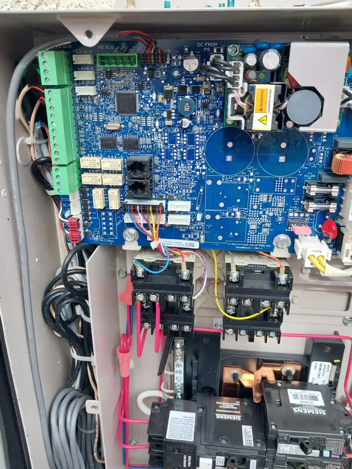 Open pool automation cabinet with a circuit board, relays and connected wiring.