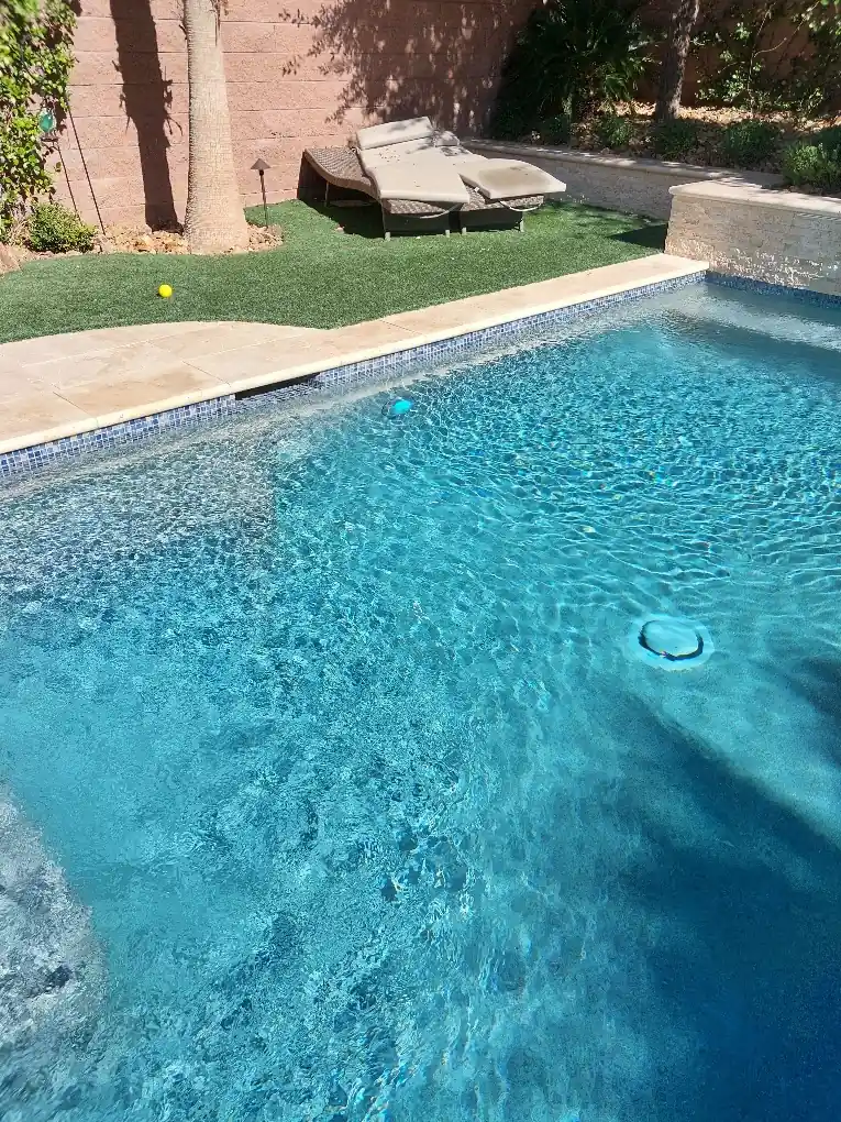 Sunlit pool water and submerged wall light.