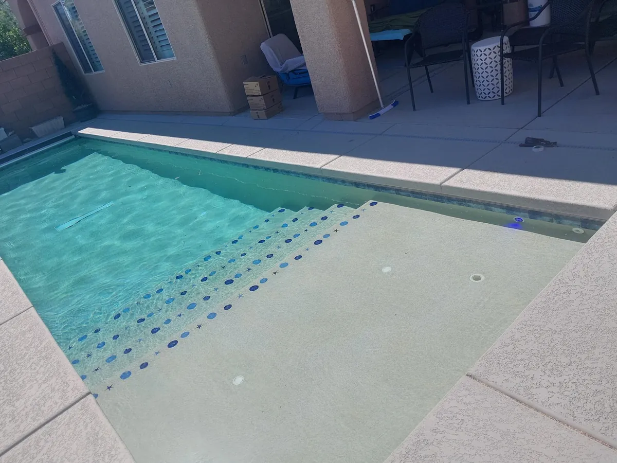 Pool entry steps and a shallow sun shelf beneath clear water.