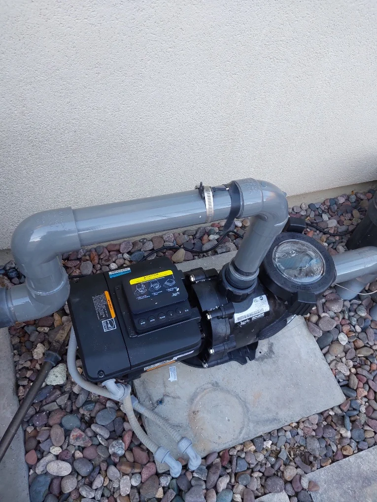 Installed variable-speed pool pump, controller and pipe unions on a residential equipment pad.