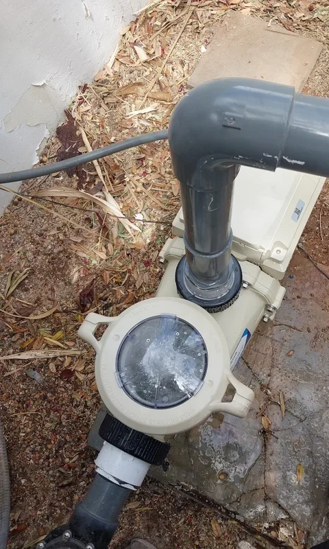 Variable-speed pool pump with a clear strainer lid and dark return plumbing.