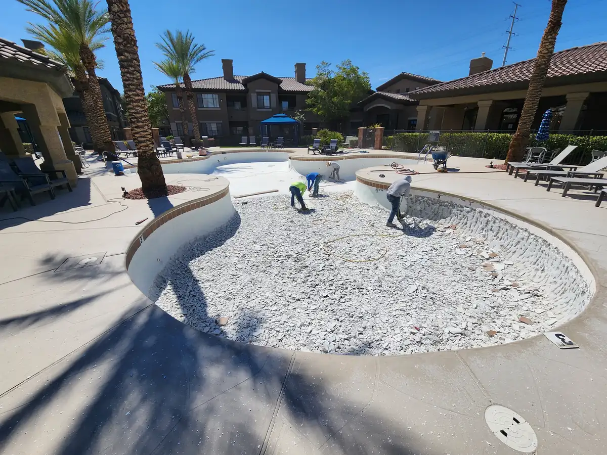 Crew and tools inside a drained pool during remodeling.