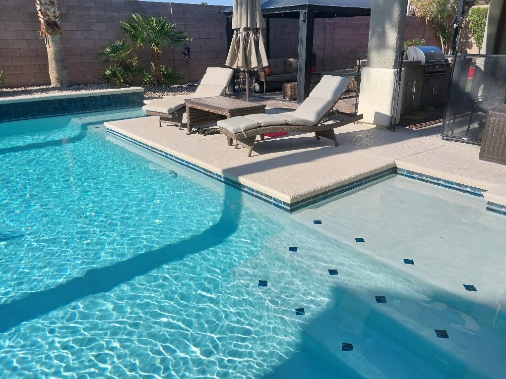 Clear residential pool with sun reflections and lounge chairs