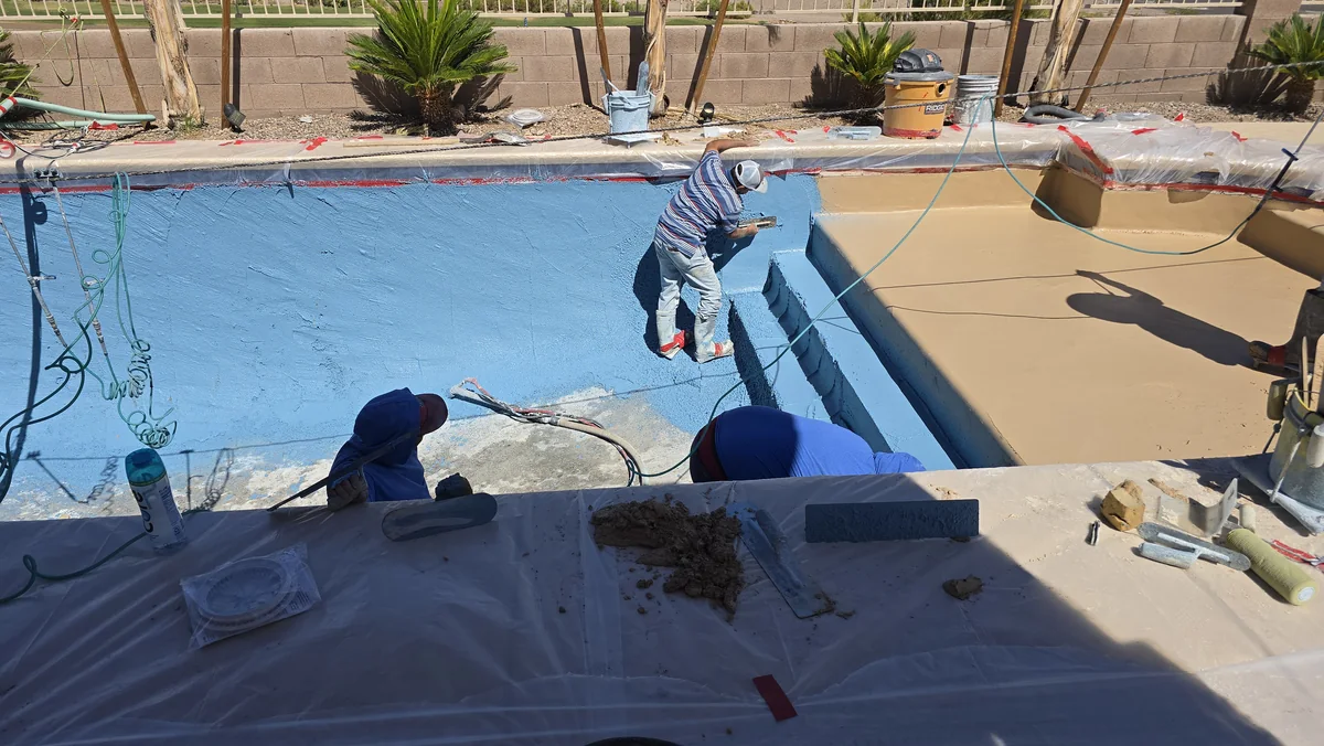 Workers finishing the surface around pool entry steps.