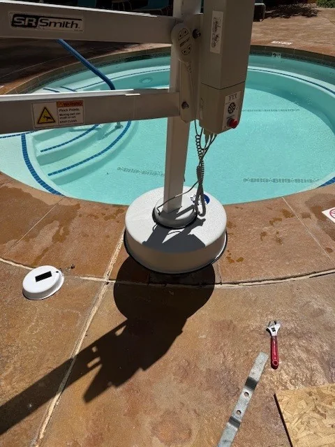 Pool lift assembly beside a pool or spa deck.