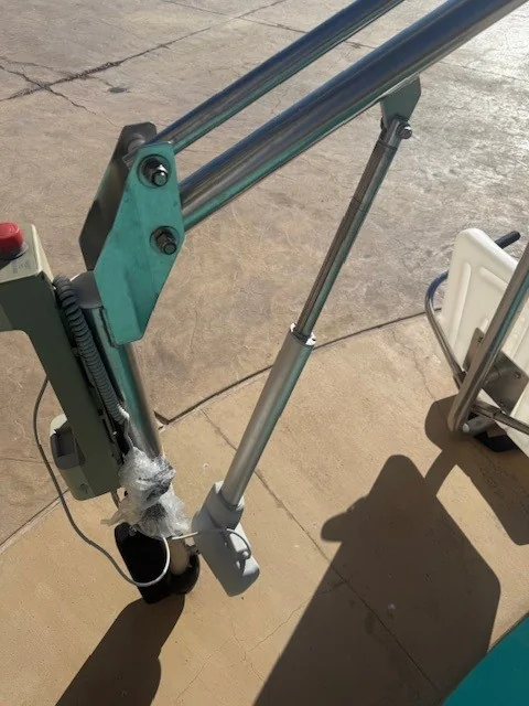 Pool lift arm and base beside deck paving.