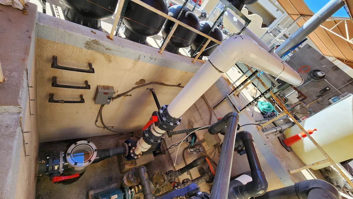Large pipes and valves in a pool equipment room.