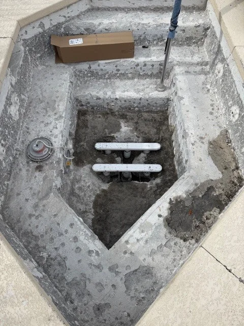 Two suction-outlet sumps exposed in a drained pool.