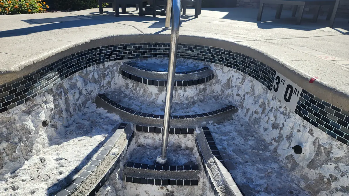 Tile-lined steps inside a drained spa during surface work.
