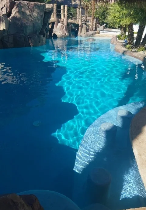 Pool water beside rocks and a waterfall.