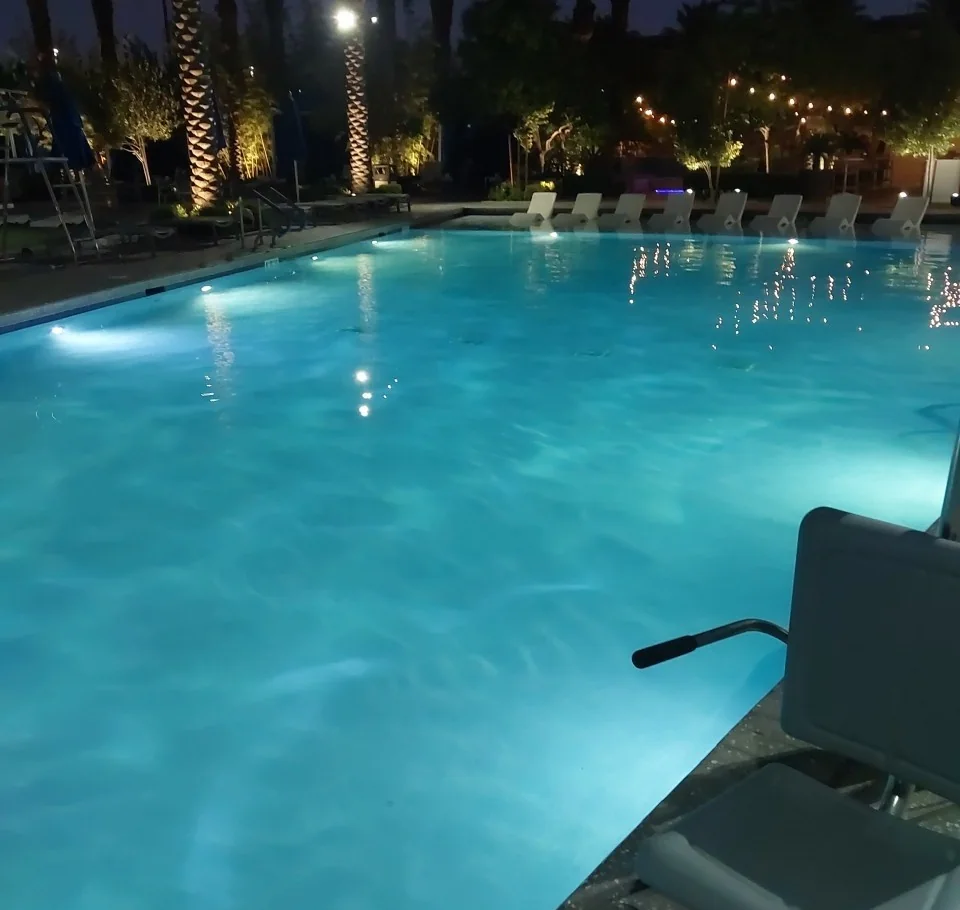 Outdoor pool with underwater lights glowing at night.