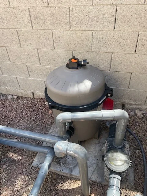 Pool filter housing and connected plumbing at an equipment pad.