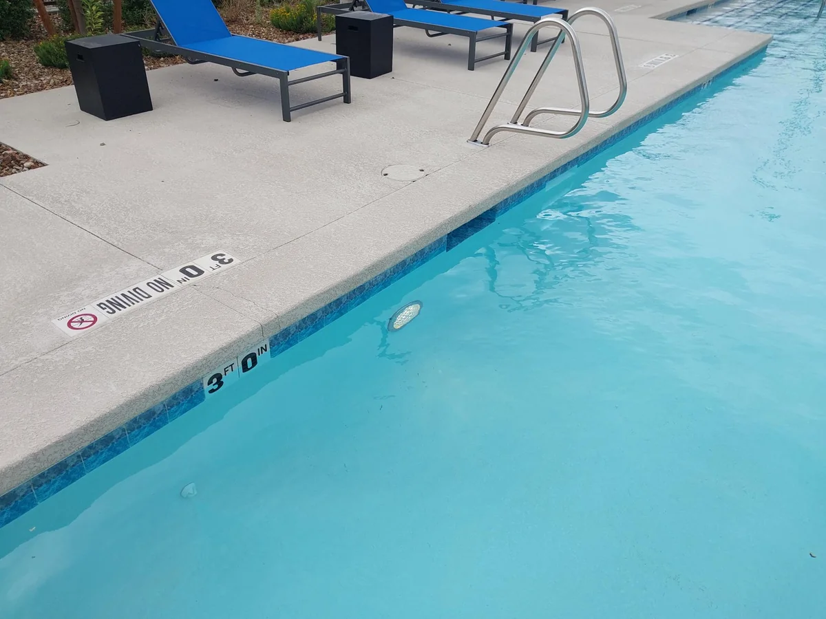 Pool water, submerged wall light and metal entry handrail.