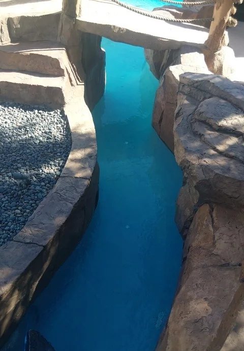 Pool water along a narrow channel beside a rock feature.